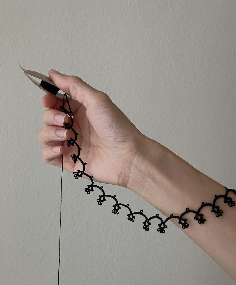 Black choker work in progress. Clover tatting shuttle. 2026.